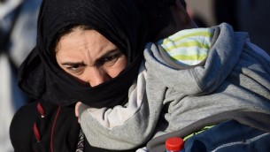 لاجئة تحمل طفلها في نقطة لجمع المهاجرين بالقرب من قرية روسزكي على الحدود المجرية-الصربية في 8 سبتمبر، 2015. (AFP PHOTO / ATTILA KISBENEDEK)