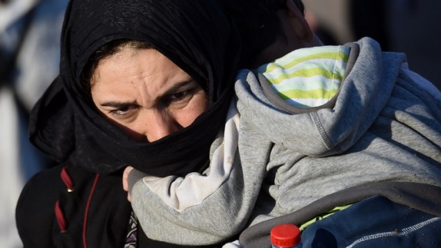 لاجئة تحمل طفلها في نقطة لجمع المهاجرين بالقرب من قرية روسزكي على الحدود المجرية-الصربية في 8 سبتمبر، 2015. (AFP PHOTO / ATTILA KISBENEDEK)