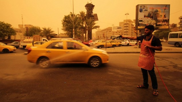 عامل عراقي يقوم برش الماء على مدرج المطار في العاصمة العراقية بغداد  في 1 سبتمبر، 2015. (AFP Photo/Haidar Mohammed Ali)