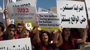 طلاب من المدارس الأهلية المسيحية يرفعون اللافتات خلال تظاهرة إحتجاجية للمطالية بمزيد من التمويل لمدارسهم، 6 سبتمبر، 2015 في القدس. (Menahem Kahana/AFP)
