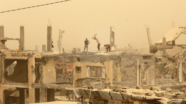عمال بناء يعملون بين الحطام في قطاع غزة خلال عاصفة رملية، 9 سبتمبر 2015 (MAHMUD HAMS / AFP)