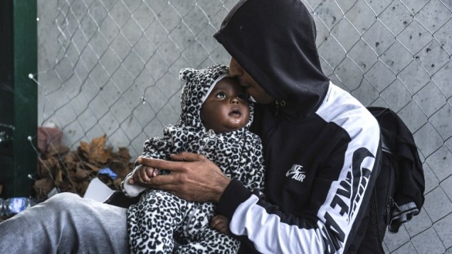 رجل يقبل طفله بينما ينتظر على الحدود بين المجر وصربيا، 15 سبتمبر 2015 (ARMEND NIMANI / AFP)