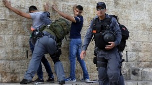 عناصر من الشرطة الإسرائيلية تقوم بتفتيش شبان فلسطينيين عند باب العامود في البلدة القديمة بمدينة القدس، 18 أكتوبر، 2015.(AFP/Ahmad Gharabli)