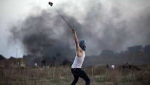 متظاهر فلسطيني يستخدم  مقلاعا لإلقاء حجارة تجاه الجنود الإسرائيليين خلال مواجهات بالقرب من السياج الحدودي بين إسرائيل ووسط قطاع غزة، 15 أكتوبر، 2015. (Mohammed Abed/AFP)