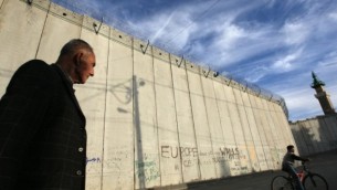 رجل فلسطيني يمر بجانب الجدار الفاصل الإسرائيلي في قرية أبو ديس في الدقس الشرقية. (Kobi Gideon/Flash90)