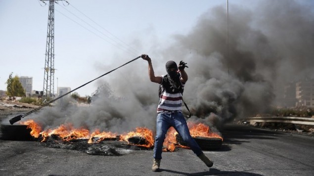 محتج فلسطيني يستخدم مقلاعا لرمي الحجارة باتجاه القوات الإسرائيلية خلال مواجهات في بيت إيل بالقرب من مدينة رام الله بالضفة الغربية، 11 أكتوبر، 2015. (AFP/Abbas Momani)
