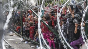لاجئون يقفون خلف سياج على الحدود بين المجر وصربيا، 16 سبتمبر 2015 (ARMEND NIMANI / AFP)