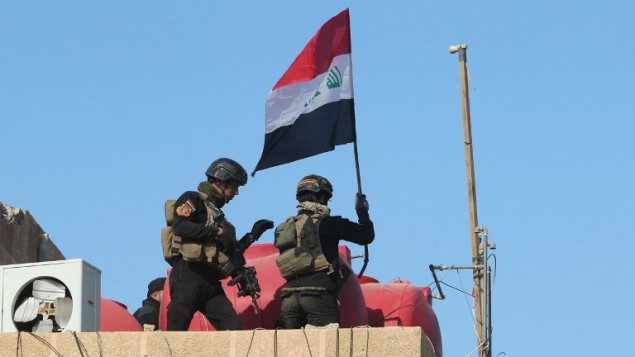 رجال جهاز مكافحة الارهاب يرفعون العلم العراقي فوق المجمع الحكومي في مدينة الرمادي بعد تحريرها من سيطرة تنظيم الدولة الإسلامية، 28 ديسمبر 2015 (AHMAD AL-RUBAYE / AFP)