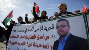 فلسطينيون يشاركون في تظاهرة بالقرب من رام الله للمطالبة بإطلاق سراح الصحافي الفلسطيني محمد القيق (الذي تظهر صورته على اللافتة) من سجن إسرائيلي، 22 يناير، 2016. (Abbas Momani/AFP)