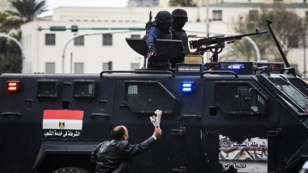 رجل مصري داعم للحكومة يقدم الازهار لقوات الشرطة الخاصة التي تحرس ميدان التحرير في القاهرة في يوم ذكرى الثورة، 25 يناير 2016 (MOHAMED EL-SHAHED / AFP)