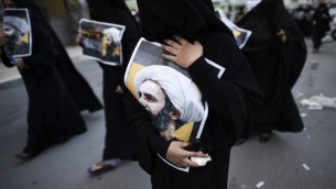سيدة بحرينية تحمل صورة رجل الدين الشيعي البارز نمر النمر خلال احتجاج على اعدامه من قبل السعودية، 3 يناير 2016 (MOHAMMED AL-SHAIKH / AFP)