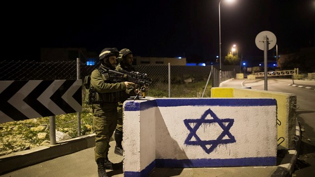 جنود إسرائيليون يقومون بالحراسة عند مفرق طرق في الضفة الغربية، 17 يناير، 2015. (Yonatan Sindel/Flash90) جنود إسرائيليون يقومون بالحراسة عند مفرق طرق في الضفة الغربية، 17 يناير، 2015. (Yonatan Sindel/Flash90)