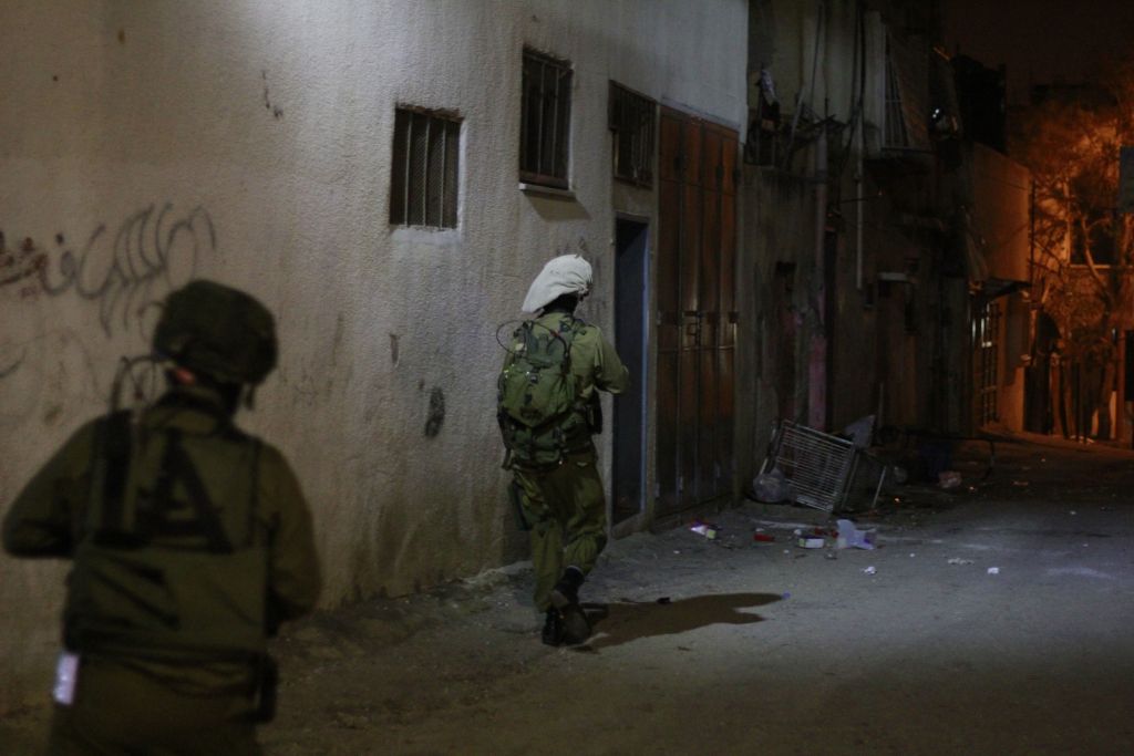 جنود يتقدمون نحو منزل مراهقين فلسطينيين اثنين يعتقد انهما شاركا في مظاهرات عنيفة في قلقيلية. يرافق الفرقة ممثل يتحدث العربية عن مكتب منسق النشاطات الحكومية في الاراضي التابع لوزارة الدفاع، ليتواسط الحديث بين الجنود وعائلات المتهمين، 14 يناير 2016 (Judah Ari Gross/Times of Israel)