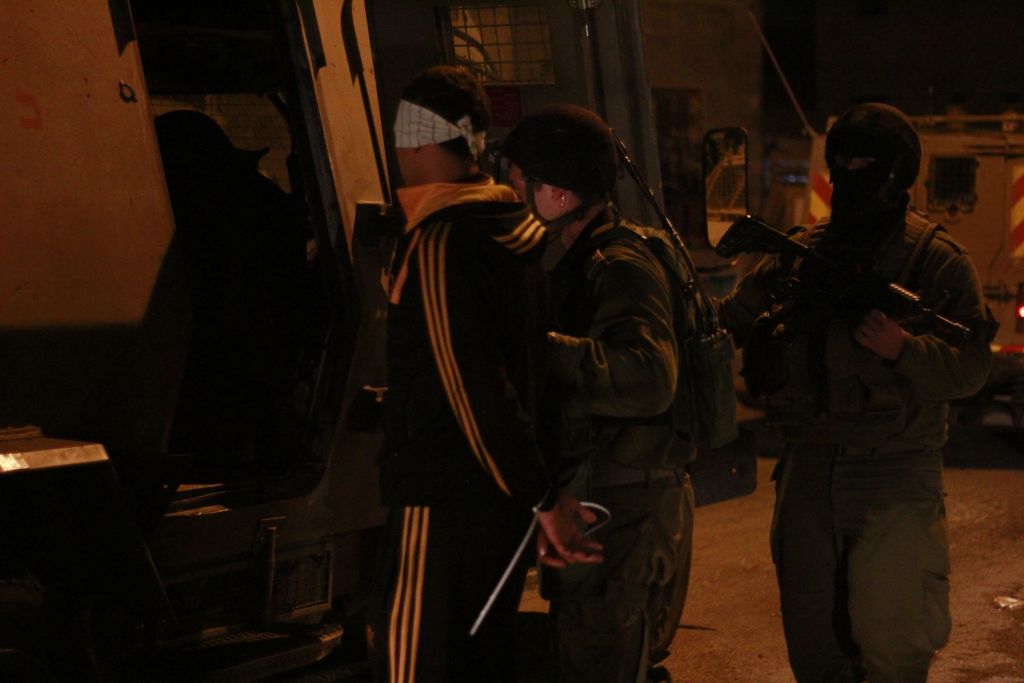 جنود يقتادون معتقل داخل ’زئيف’، وهي مركبة مدرعة لنقل الاشخاص، في قلقيلية، 14 يناير 2016. أمر القائد نمرود كيبولسكي الجنود بنقل المراهق الفلسطيني بعيدا عن اهله قبل تعصيب عينيه وتكبيل يديه، كي لا يراه والده مكبل، قال كيبولسكي (Judah Ari Gross/Times of Israel)