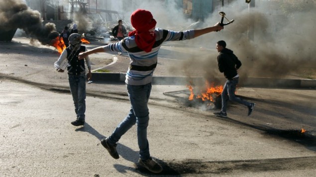 مراهقين فلسطينيين يرشقون قوات الامن الإسرائيلية بالحجارة خلال اشتباكات في مدينة الخليل في الضفة الغربية، 20 نوفمبر 2015 (AFP/Hazem Bader)