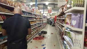 شرطي اسرائيلي ييجل الادلة في ساحة هجوم طعن داخل متجر في مستوطنة في الضفة الغربية، 18 فبراير 2016 (Israel Police)