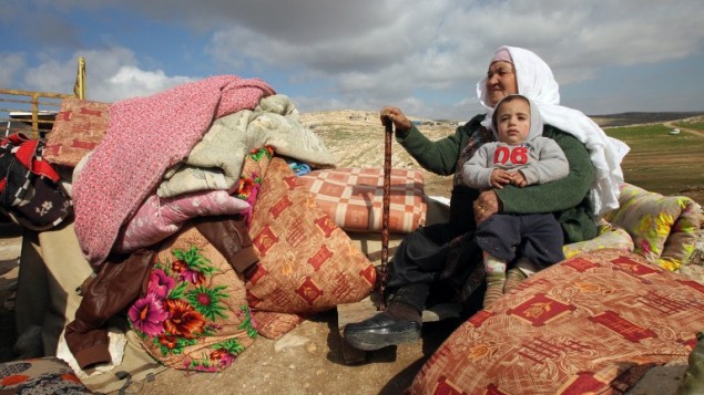 سيدة فلسطينية تجلس وهي تحمل طفبلا إلى جانب ما تم إنقاذه من بقايا منزلهما بعد أن قامت الجرافات الإسرائيلية بهدمه في منطقة عسكرية متنازع عليها في مسافر جنبا، التي تضم عددا من القرى، جنوبي مدينة الخليل في الضفة الغربية، 2 فبراير، 2016.  (AFP / HAZEM BADER)