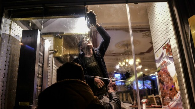 رجلان ينظفان شباك مطعم يقع بالقرب من موقع تفجير انتحاري في شارع استقلال في مركز اسطنبول، 19 مارس 2016 (Bulent Kilic/AFP)