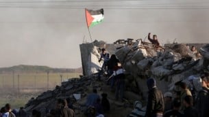 من الأرشيف: متظاهر فلسطيني يرفع العلم الفلسطيني خلال مواجهات مع القوات الإسرائيلية على الحدود مع إسرائيل في الضواحي الجنوبية لمدينة غزة في 4 ديسمبر، 2015. (AFP PHOTO/MAHMUD HAMS)