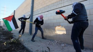 فلسطينيون يقومون بتحطيم مقطع من الجدار الفاصل في الضفة الغربية في قرية بير نبالا، بين القدس ورام الله، 8 نوفمبر، 2014. (STR/Flash90)