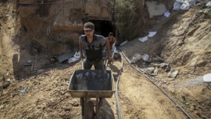 من الأرشيف: رجال فلسطينيون يعملون عند مدخل نفق يُستخدم لتهريب البضائع بين مصر وقطاع غزة بعد أن قام الجيش المصري بضخ مياه البحر فيه، في رفح جنوبي قطاع غزة، 1 اكتوبر، 2015. (Abed Rahim Khatib/ Flash90)