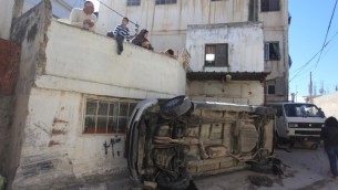 فلسطينيون ينظرون الى الدمار الناتج عن اشتباكات بين السكان وقوات الامن الإسرائيلية في مخيم قلنديا، 1 مارس 2016 (Flash90)