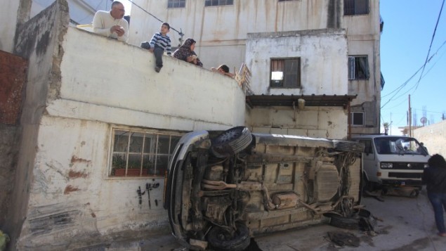فلسطينيون ينظرون الى الدمار الناتج عن اشتباكات بين السكان وقوات الامن الإسرائيلية في مخيم قلنديا، 1 مارس 2016 (Flash90)
