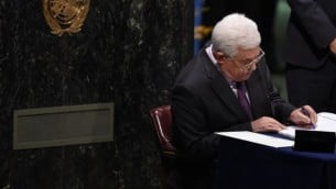 رئيس السلطة الفلسطينية محمود عباس يوقع على أوراق خلال مراسم التوقيع على اتفاق باريس التاريخي في قاعة الجمعية العامة للأمم المتحدة في 22 أبريل، 2016. (AFP PHOTO/TIMOTHY A. CLARY)
