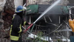عنصر من قوات الاطفاء التابعة للدفاع المدني الفلسطيني يقوم باخماد الحريق الذي اندلع في اعقاب "عملية تفجير محكمة للخزنة" في مصرف في رام الله  14 ابريل 2016 (صورة شاشة, يوتوب)