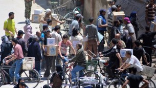 فلسطينيون وسوريون يتلقون رزم مساعدات من وكالة اونروا في مخيم اليرموك جنوب دمشق، 12 مايو 2016 (RAMI AL-SAYED / AFP)