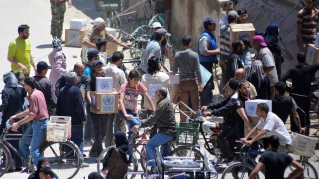 فلسطينيون وسوريون يتلقون رزم مساعدات من وكالة اونروا في مخيم اليرموك جنوب دمشق، 12 مايو 2016 (RAMI AL-SAYED / AFP)