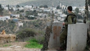 صورة توضيحية لجندي إسرائيلي يقوم بحراسة مستوطنة كدوميم، مع قرية قدوم الفلسطينية في الخلفية، 13 نوفمبر، 2009. (Gili Yaari/Flash90)