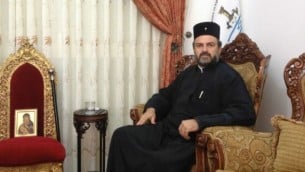 الأب جبرائيل نديف، في غرفة المعيشة، إلى جانب أيقونة لمريم العذراء، التي يقول بأنه يومن بأنها أنقذت حياته في حادث طرق في 2011. (Mitch Ginsburg/Times of Israel)