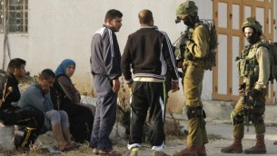 جنود إسرائيليون يتحدثون مع فلسطينيين بعد دخول الجيش الإسرائيلي قرية يطا في الضفة الغربية، 6 يونيو، 2016. (AFP PHOTO / HAZEM BADER)