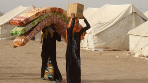 نازحون عراقيون فروا من مدينة الفلوجة، معقل تنظيم الدولة الإسلامية، يحملون الفرشات ورزم مساعدات في مخيم يقع حوالي 30 كلم جنوب المدينة، 9 يونيو 2016 (MOADH AL-DULAIMI / AFP)