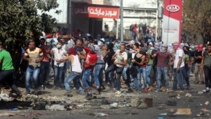 متظاهرون فلسطينيون يرشقون القوات الإسرائيلية بالحجارة عند حاجز حوارة، جنوبي مدينة نابلس في الضفة الغربية، 11 أكتوبر، 2015. (Flash90)