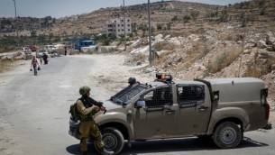 الجنود الإسرائيليون يقفون عند حاجز في مدخل بلدة يطا الفلسطينية في الضفة الغربية، 9 يونيو، 2016. (Wisam Hashlamoun/Flash90)
