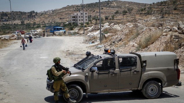 الجنود الإسرائيليون يقفون عند حاجز في مدخل بلدة يطا الفلسطينية في الضفة الغربية، 9 يونيو، 2016. (Wisam Hashlamoun/Flash90) الجنود الإسرائيليون يقفون عند حاجز في مدخل بلدة يطا الفلسطينية في الضفة الغربية، 9 يونيو، 2016. (Wisam Hashlamoun/Flash90)
