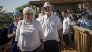 والدا هاليل يافا أريئيل، التي قُتلت في هجوم طعن في كريات أربع، ومئات المناصرين يصلون إلى الحرم القدسي في البلدة القديمة يوم الثلاثاء، 12 يوليو، 2016. (Yonatan Sindel/Flash90)