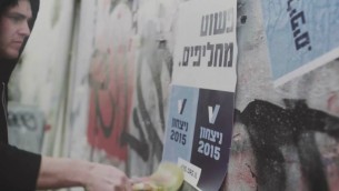 ناشط في مجموعة V15 يعلق ملصق ينادي لتغيير الحكومة (screen capture: YouTube/Victory2015)
