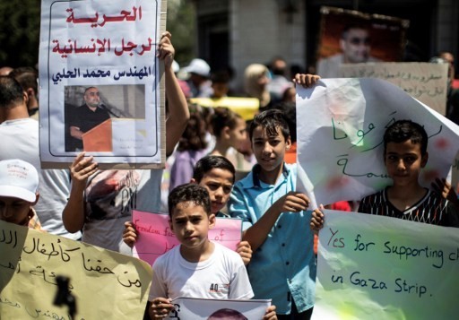أطفال فلسطينيون يحملون صورا لمحمد الحلبي (من اليسار)، مدير فرع ’وورلد فيجين’ في غزة، منظمة غير حكومية مقرها في الولايات المتحدة، خلال احتجاج تضامني معه في مدينة غزة في 7 أغسطس، 2016. (AFP PHOTO / MAHMUD HAMS)