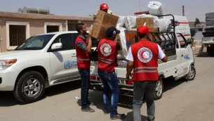 موظفو الهلال الاحمر السوري يوزعون رزم مساعدات في مركز اقامة مؤقت في بلدة حرجلة التي تحت سيطرة النظام، 27 اغسطس 2016 (AFP/Youssef KARWASHAN)