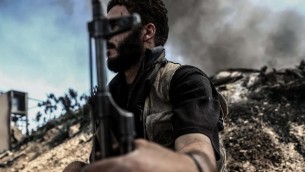مقاتل من "جيش الإسلام" يجلس القرب من نيران تتصاعد على خط المواجهة، التي يستخدمها المقاتلون للإحتماء، في قرية تل الصوان في منطقة دوما التي تعتبر معقلا للمتمردين، في ريف دمشق، 5 سبتمبر،  2016.  (AFP PHOTO / Sameer Al-Doumy)