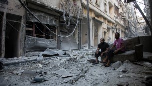 سوريون يجلسون ويتفحصون الحطام بعد غارة جوية في حي يقع تحت سيطرة المعارضة في مدينة حلب السورية، 18 سبتمبر 2016 (AFP/Karam al-Masri)