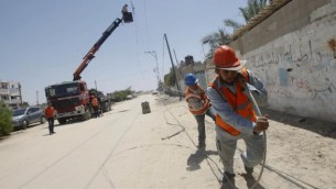 عمال من شركة الكهرباء الفلسطينية يقومون بسحب خط كهرباء، تدمر الكثير منها في أعقاب غارة إسرائيلية في رفح جنوبي القطاع، 6 أغسطس، 2014. (photo credit: AFP/SAID KHATIB)