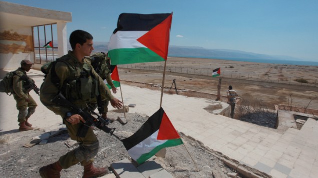 صورة توضيحية لجنود اسرائيليون يمرون بجانب اعلام فلسطينية بالقرب من مدينة اريحا في الضفة الغربية (Issam Rimawi/Flash90)