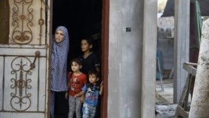 عائلة فلسطينية تطل من باب منزلها في حي الشجاعية شرقي مدينة غزة في أعقاب قصف إسرائيلي في 5 أكتوبر، 2016. (AFP/MOHAMMED ABED)