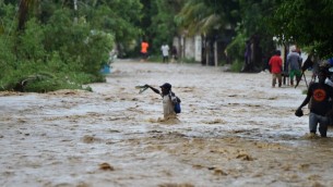 اشخاص يحاولون عبور نهرطافح في جنوب هايتي مع وصول الاعصار ماثيو، 5 اكتوبر 2016 (HECTOR RETAMAL / AFP)