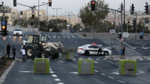 عناصر الشرطة الإسرائيلية يقفون عند حاجز إسمنتي تم وضعه من قبل قوى الأمن الإسرائيلية على طريق يربط بين حي بيت حنينا في القدس الشرقية وغربي القدس، في 11 أكتوبر، 2016، عشية يوم الغفران. (AFP/Ahmad Gharabli)