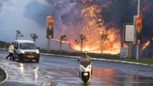 سائقون إسرائيليون يمرون أمام حريق مستعر في مدينة حيفا شمال إسرائيل، 24 نوفمبر، 2016. (Jack Guez/AFP)